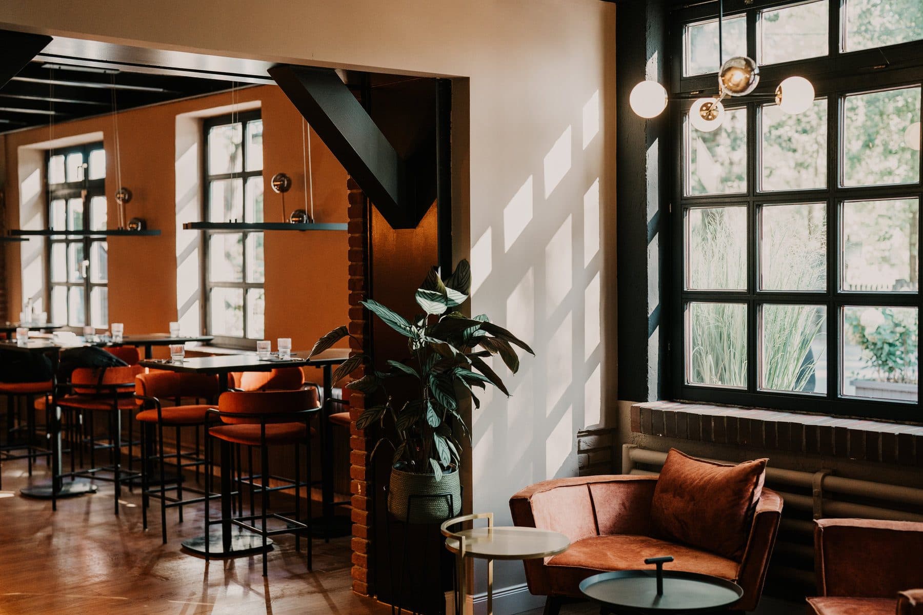 Bar und Lounge im Herzstykke mit Lederhockern, warmem Licht und Blick in den Garten