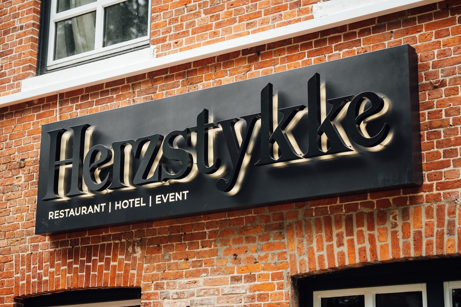 Backsteinfassade des Herzstykke mit Schild „Restaurant | Hotel | Event“